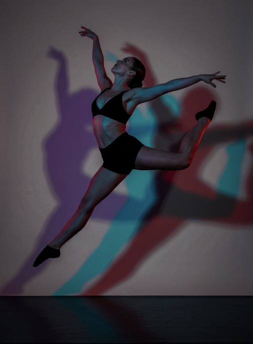 Dancer mid-leap with colored shadows
